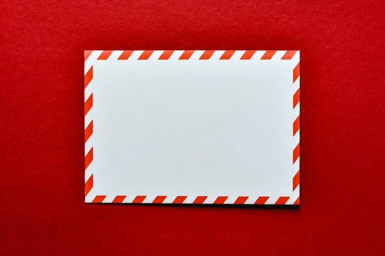 A blank white envelope with red stripes on a vibrant red background, perfect for postal themes.